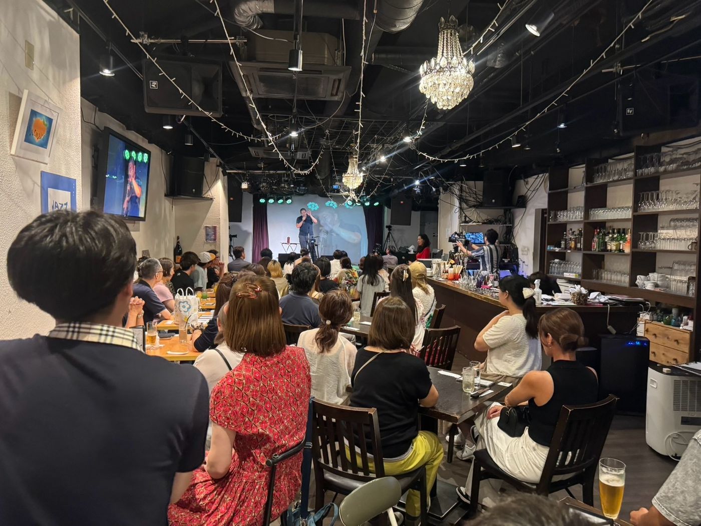 第1回おしゃべりナイトの会場。ステージで話すしのっぴと、客席を埋めるお客さん